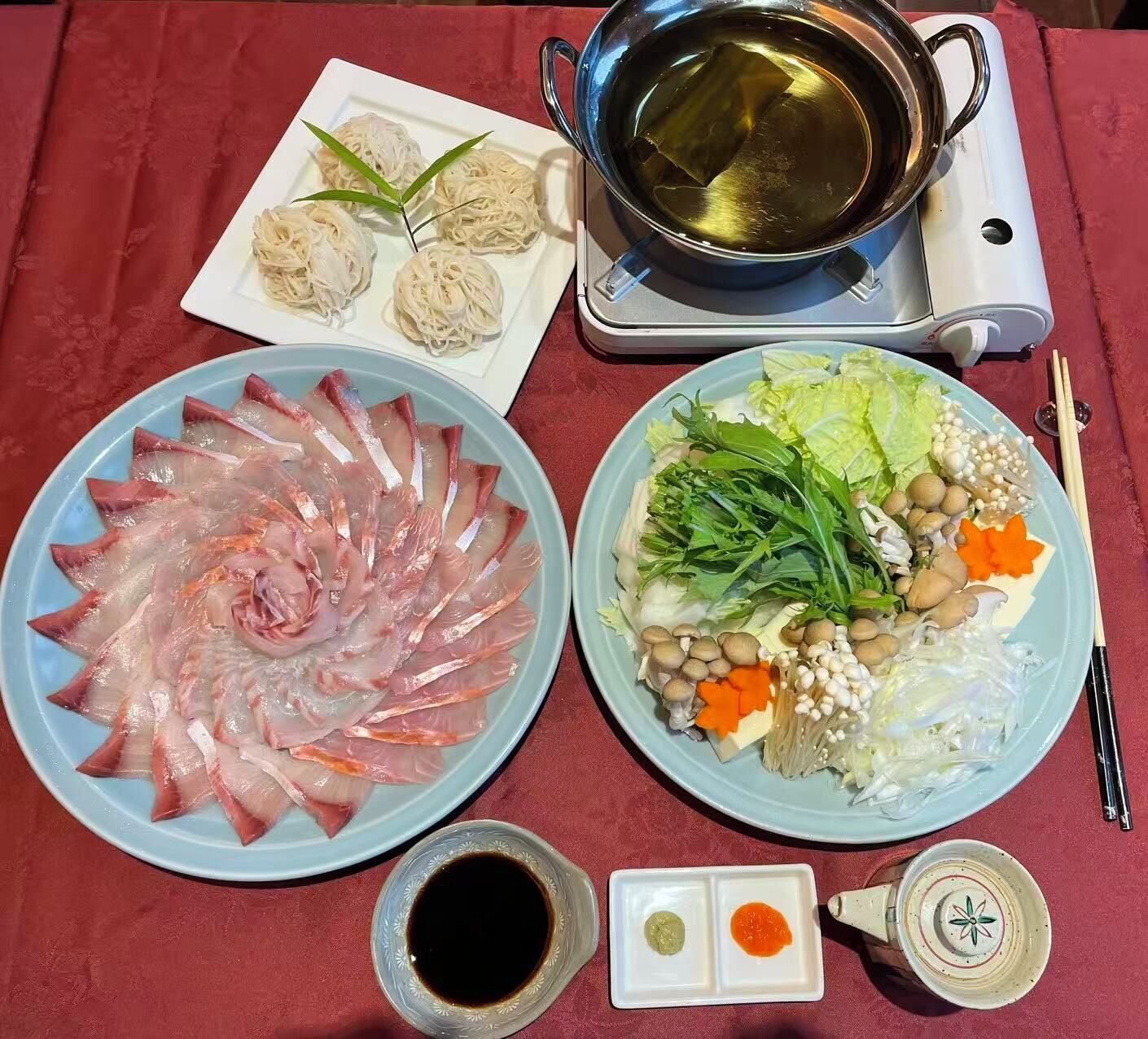 A table with various dishes, a pot of boiling water, and condiments.