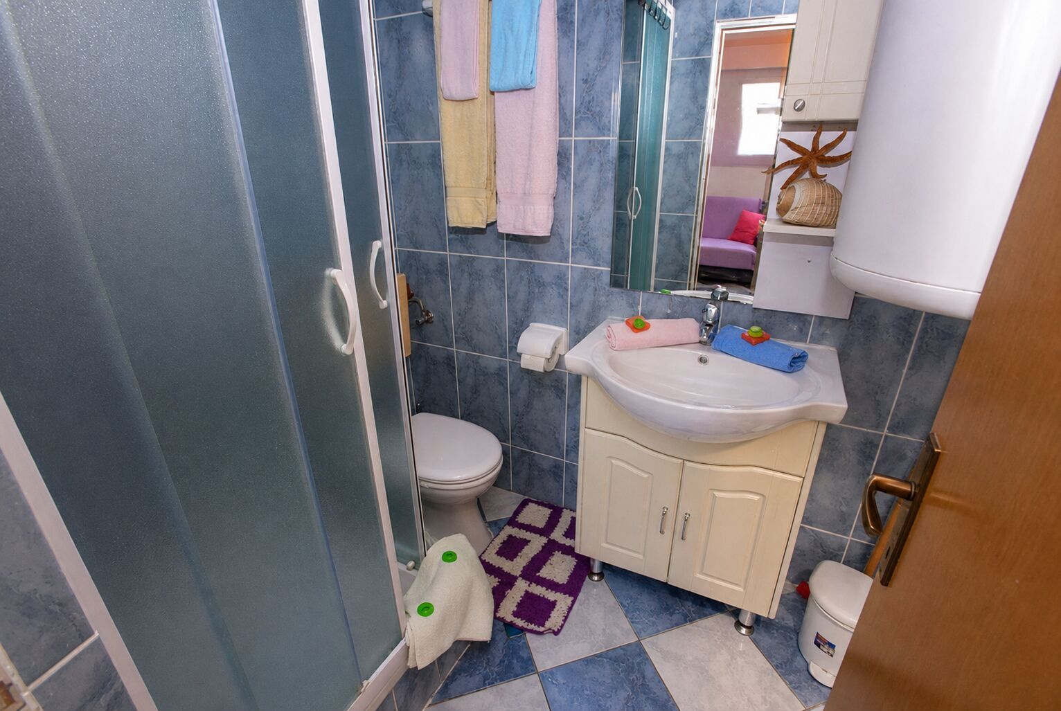 Et badeværelse med toilet, håndvask og bruseniche.