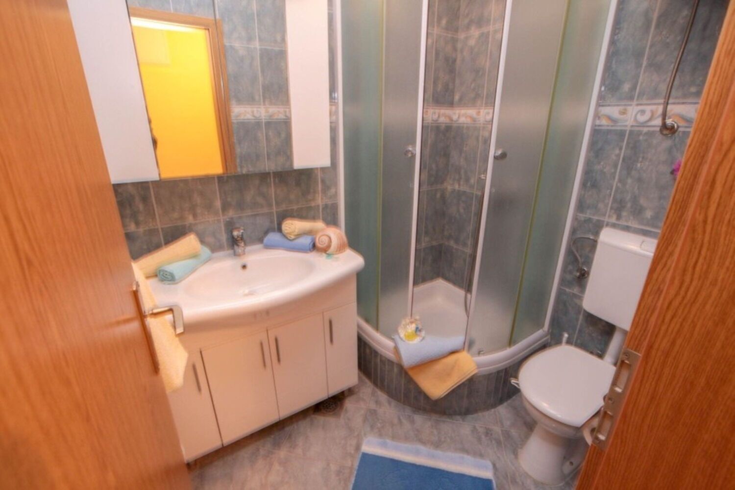 Een kleine badkamer met een wastafel, toilet en douche.