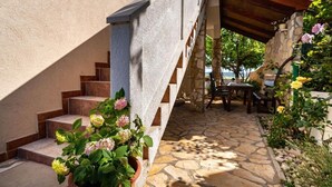 A stone staircase leading to a covered outdoor area with a table and chairs. - Apartment San (Povljana)