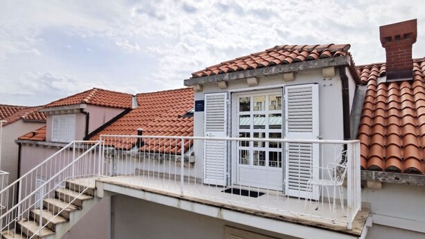 A residential building with red-tiled roofs, white shutters, and a white balcony railing. - Apartment Anja (Dubrovnik)