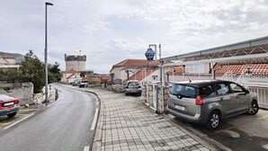 A street with parked cars, a castle-like structure, and a signboard. - Apartment Anja (Dubrovnik)
