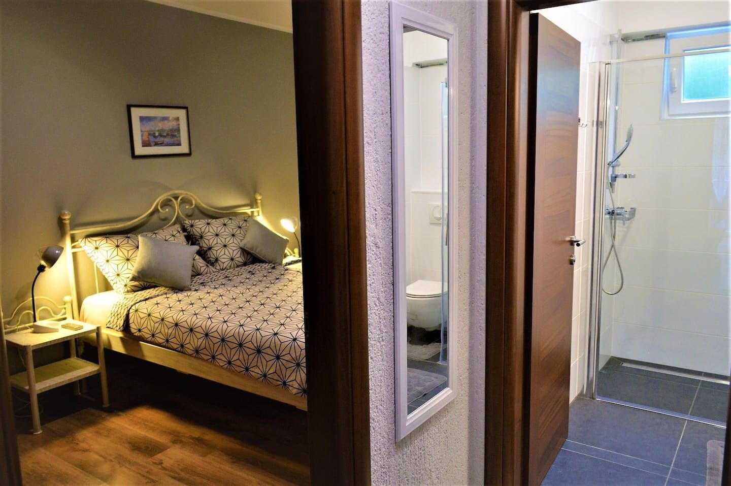 Une chambre à coucher avec un lit, une table de chevet, une lampe et un tableau encadré au mur.