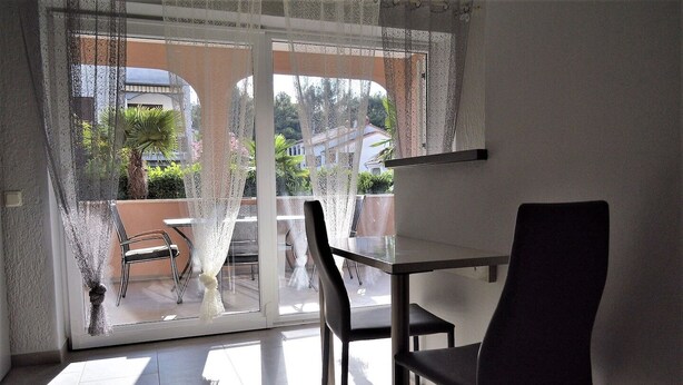 Varanda com porta de vidro, uma mesa e duas cadeiras.