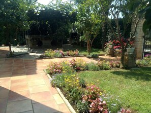 A garden pathway with a variety of flowering plants and trees. - Apartments Leonard (Porec)