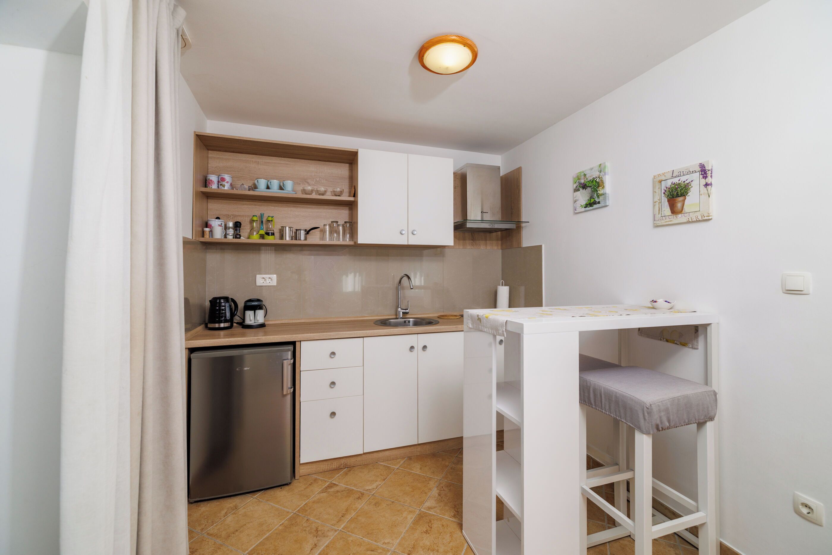 A compact kitchen with a dishwasher, a sink, and a small table with a bench.