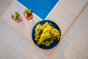 A blue plate of yellow grapes on a tiled floor next to two glasses of a pink drink with a garnish. - House Jurica (Omis)