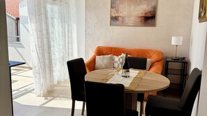 Un área de comedor con una mesa redonda, sillas, un sofá y un equipo de aire acondicionado.