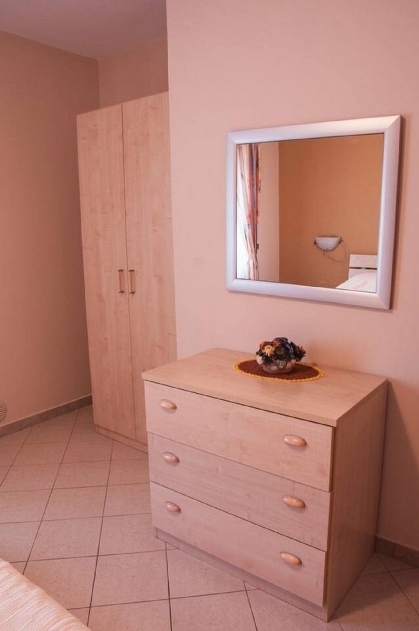 Une chambre à coucher avec une armoire en bois, une table de chevet avec un miroir et un lit.