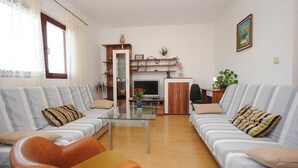 Ein Wohnzimmer mit zwei Sofas, einem Couchtisch, einem Fernseher und einem Schrank.