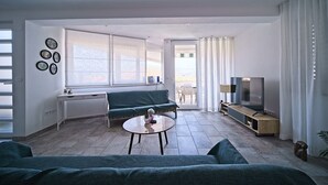 Een moderne woonkamer met een bank, een salontafel, een televisie en een raam met gordijnen.