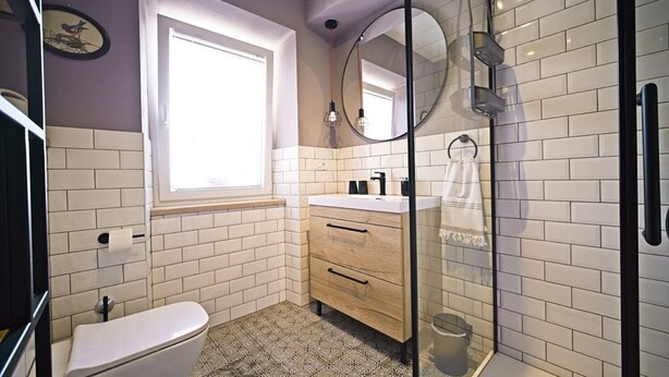 Ein modernes Badezimmer mit Toilette, Waschbecken mit Spiegel und einer Duschkabine.