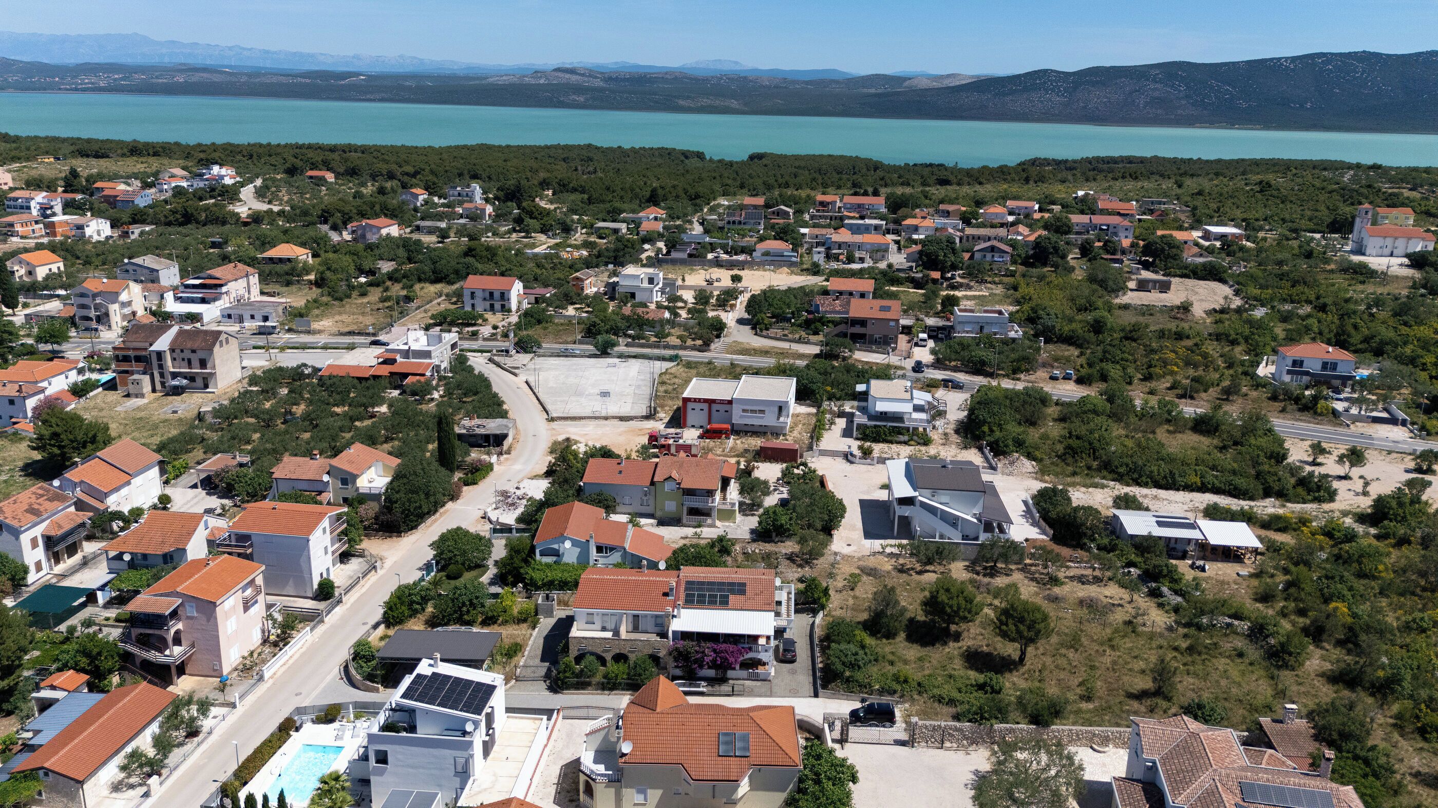 Zona residencial con casas, calles y una masa de agua al fondo.