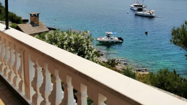 Ein Balkon mit Blick auf das Meer, Boote und eine felsige Insel.