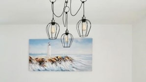 Ein Essbereich mit einem weißen Tisch, schwarzen Stühlen und einem Gemälde eines Leuchtturms an der Wand.