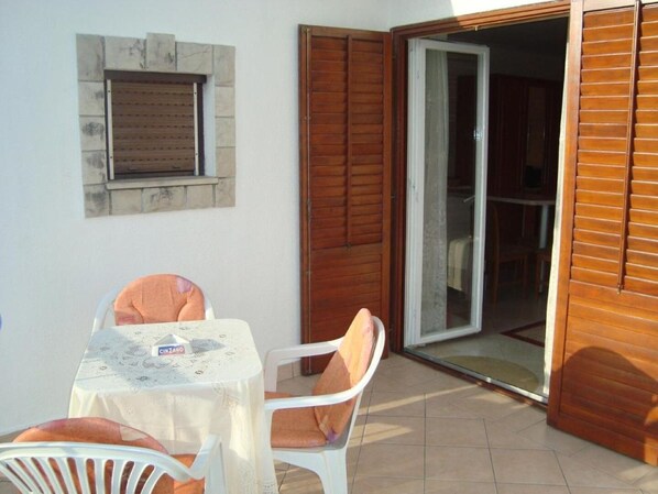 Eine Terrasse mit Tisch und Stühlen, eine Glastür und ein Fenster mit Steinrahmen.