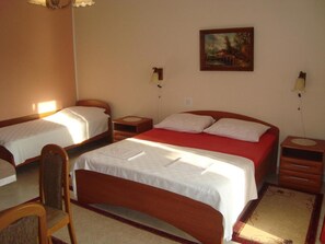 A room with two single beds, a larger bed, a chair, a small table, and a painting on the wall. - Apartment Marie (Omisalj)