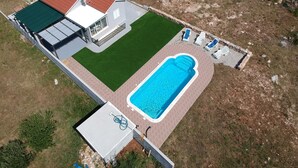 An aerial view of a property with a swimming pool, a covered patio, and a fenced yard. - House Nane Garden (Supetar)