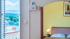 Ein Hotelzimmer mit Bett, Nachttischlampe und Blick auf eine Berglandschaft durch ein Fenster.