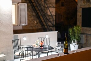 Ένας χώρος τραπεζαρίας με ένα τραπέζι και καρέκλες, ένα μπουκάλι κρασί και δύο ποτήρια κρασιού σε ένα μπαλκόνι.