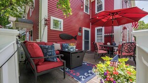 A red house with a deck, outdoor furniture, and a red umbrella. - Hospitality as Sweet as Apple Pie! (Stonington)