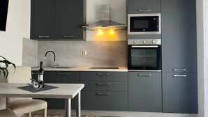 Une cuisine moderne avec des meubles de couleur sombre, un four encastré, un four à micro-ondes et une cuisinière à gaz.