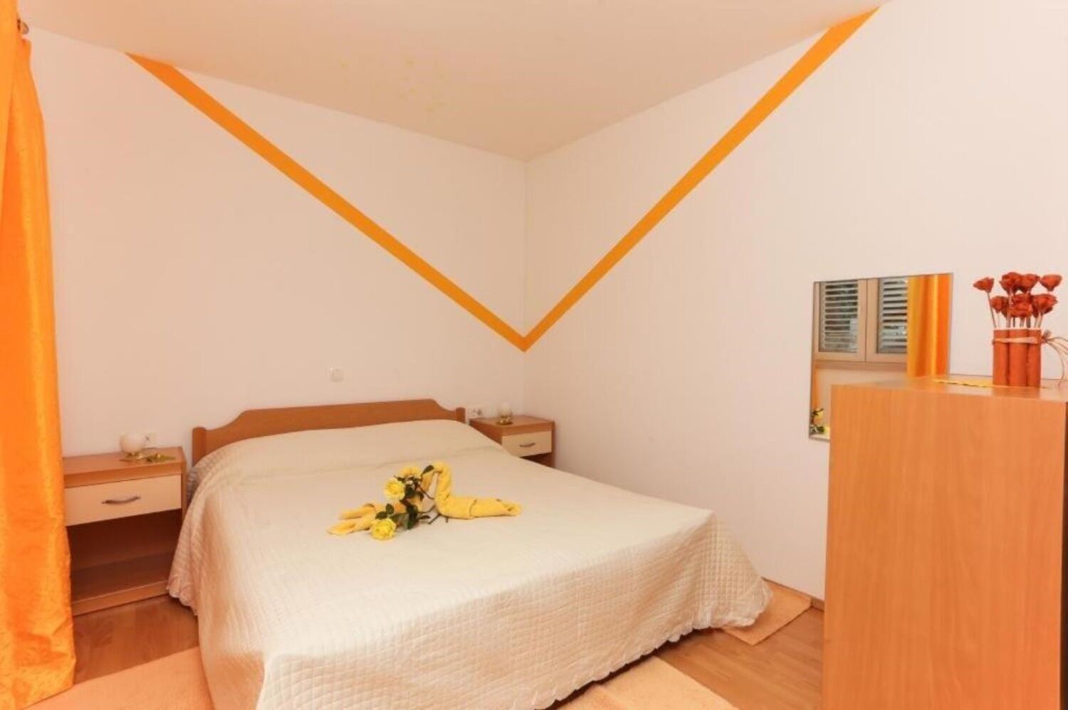A bedroom with a bed, nightstands, a wooden dresser, and a mirror.