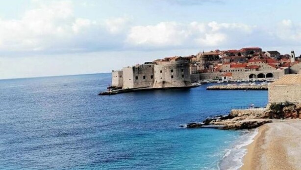 Un pueblo costero con una imponente fortaleza histórica que domina el mar.