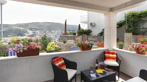 Un balcón con muebles de mimbre, plantas en macetas y vistas a la ciudad.