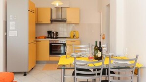 Cocina compacta con comedor, que incluye un refrigerador, horno y cafetera.