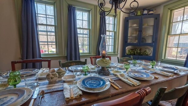 A dining room with a long table set for a meal, featuring vintage china and glassware. - A Mystic Stay as Sweet as Apple Pie! (Stonington)