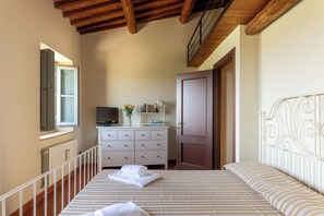 A bedroom with a bed, a dresser, a television, and a door. - Executive apartment in Borgo di Matraia (Matraia)
