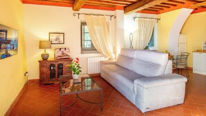 A living room with a sofa, a glass coffee table, a wooden cabinet, and a TV on the wall. - Executive apartment in Borgo di Matraia (Matraia)