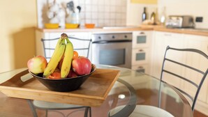 A dining table with a glass top, a wooden tray, and a bowl of fruit. - Executive apartment in Borgo di Matraia (Matraia)
