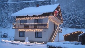 A two-story building with a snow-covered roof and exterior lights. - Apartments Dar (Lokve)