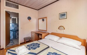 A hotel room with a bed, a desk, a chair, a small stool, a bathroom with a sink, and a mirror. - Apartments Dusan (Rab)
