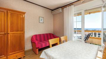 A room with a bed, a wooden wardrobe, a sofa, and a table.