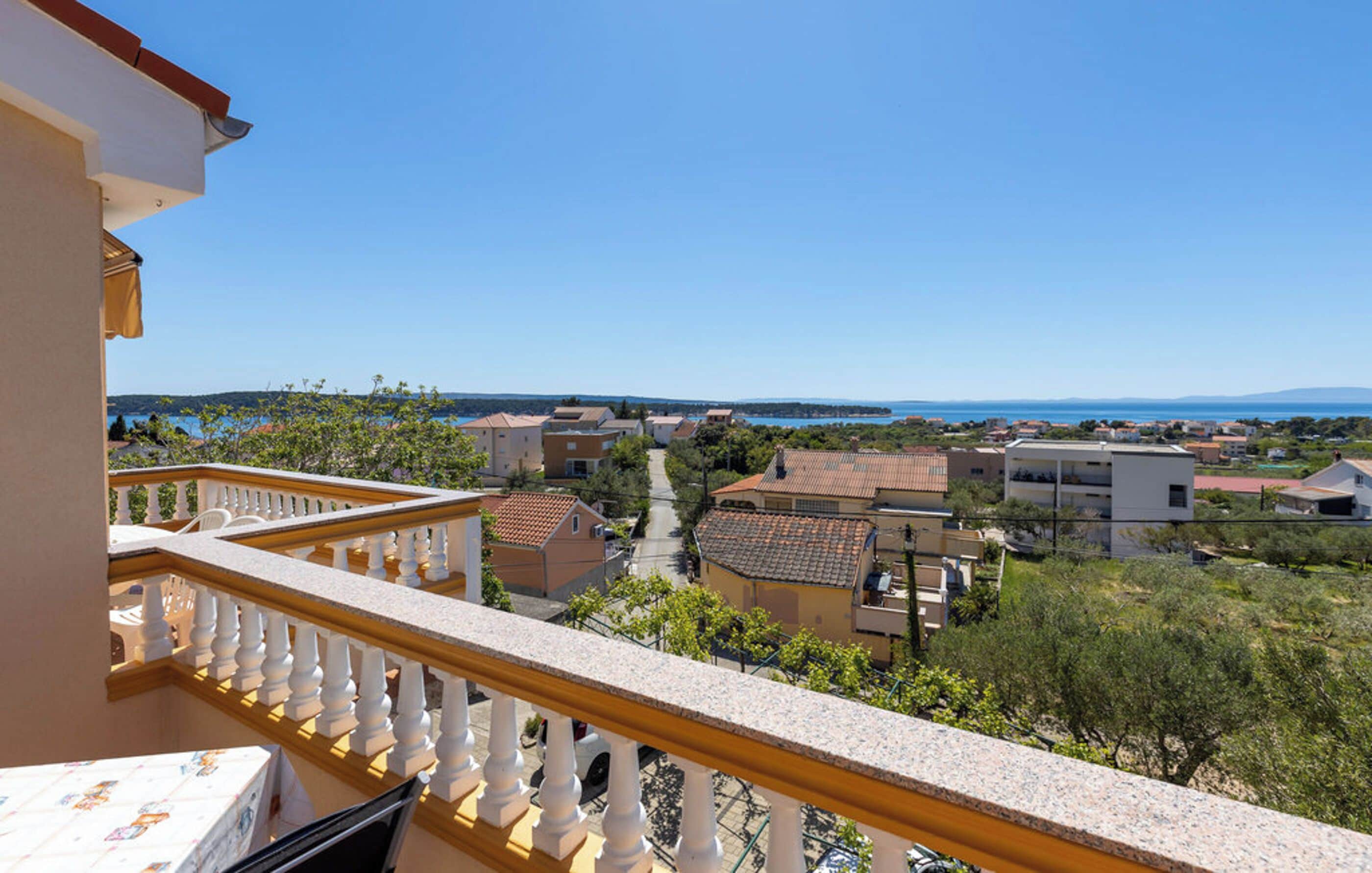 A balcony with a view of a coastal town, including houses and a body of water.