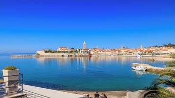 A coastal town with a prominent tower, calm waters, and a clear blue sky.