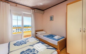 A room with two beds, a wardrobe, a window with curtains, and a balcony. - Apartments Dusan (Rab)