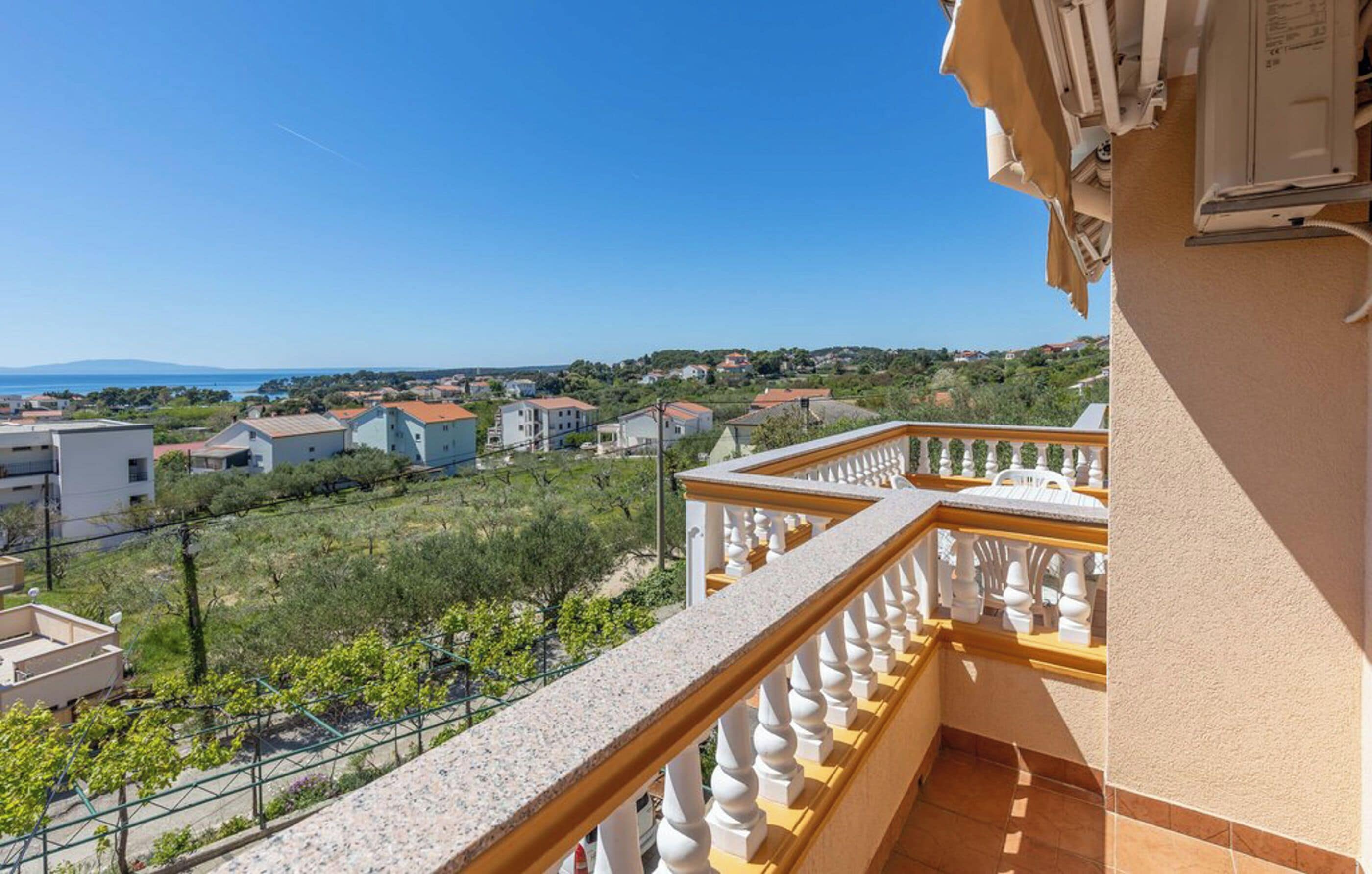A balcony with a view of a residential area, a clear sky, and distant mountains.