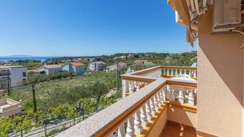 A balcony with a view of a residential area, a clear sky, and distant mountains.
