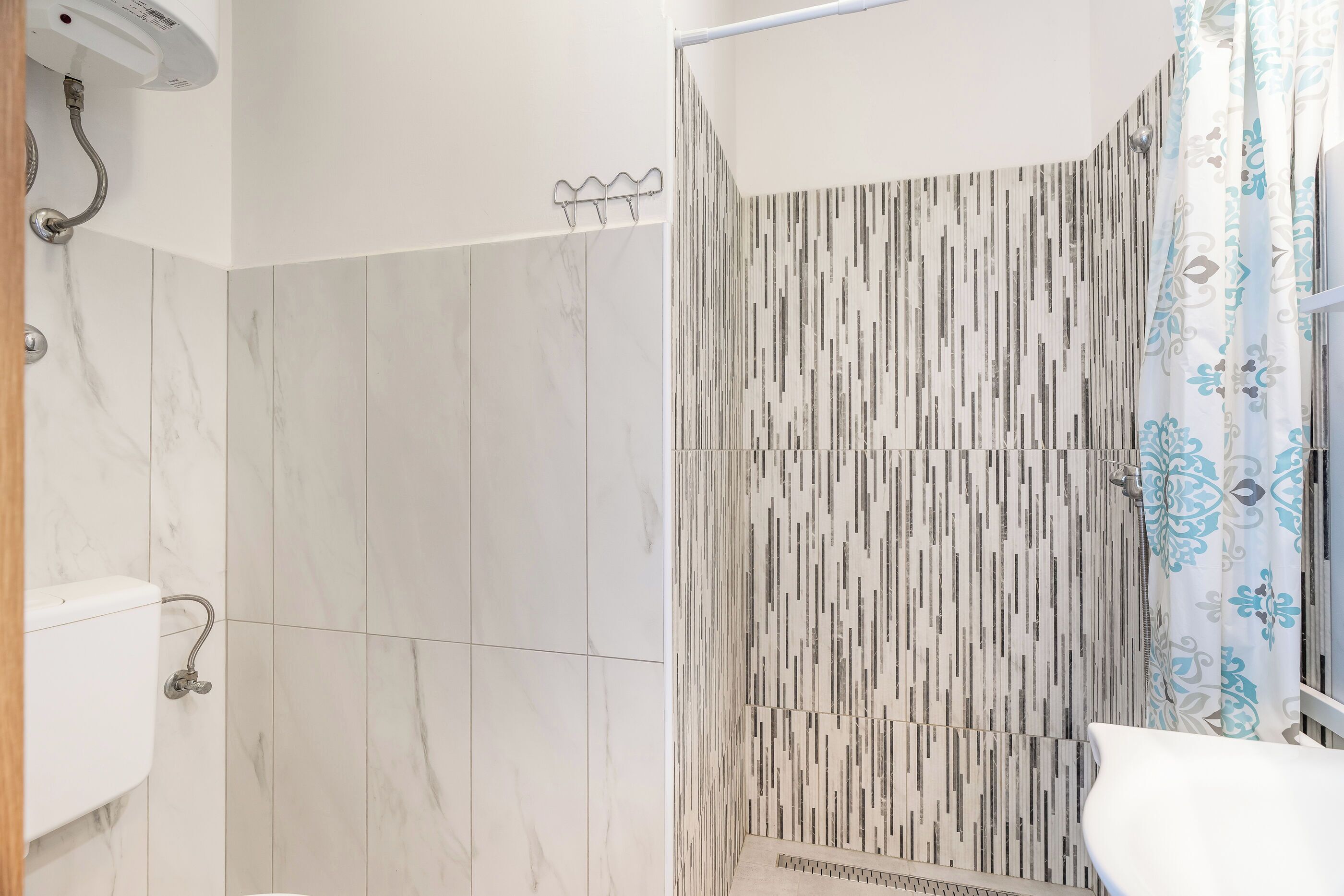 Une salle de bain moderne avec un espace douche agrémenté d’un rideau de douche à rayures verticales et de toilettes blanches.