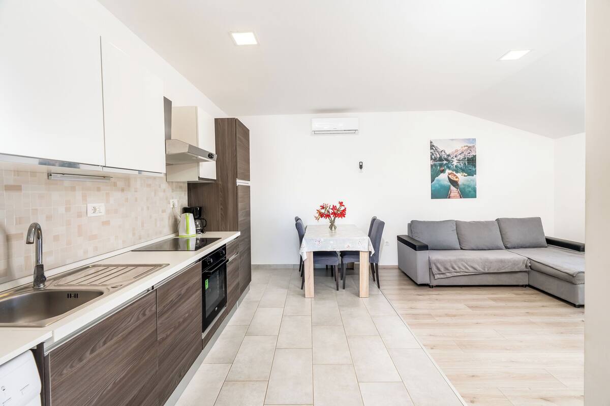A modern kitchen with a sink, stove, and dining area with a table and chairs.