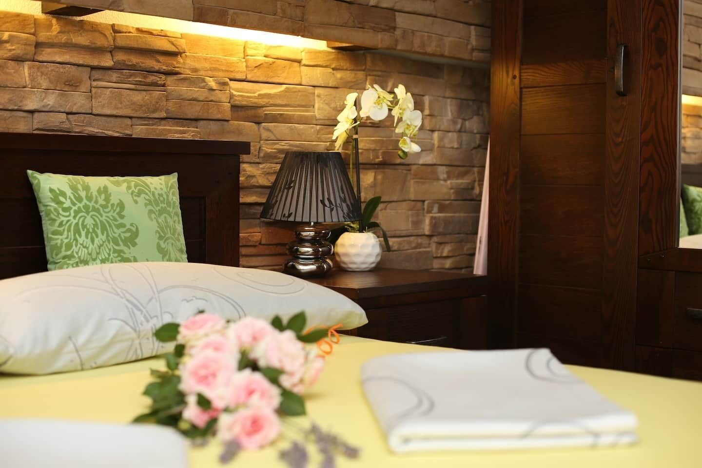 A neatly made bed with a pillow, a bedside lamp, and a vase with flowers.