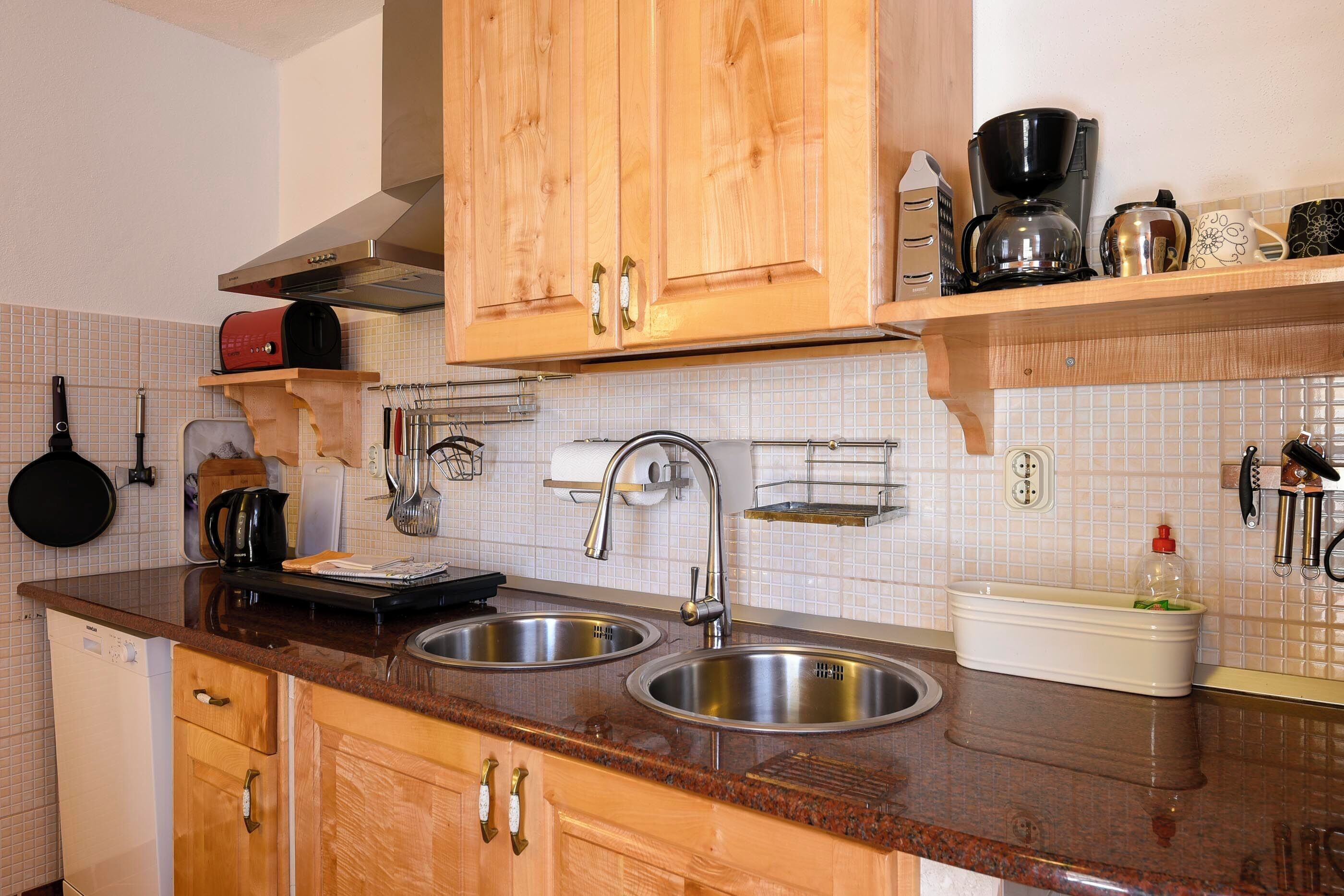 Una cocina con armarios de madera, lavamanos de acero inoxidable, una cafetera y un tostador.