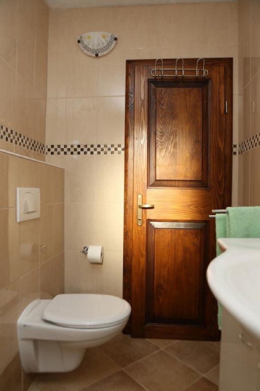 Baño con puerta de madera, inodoro y lavamanos.