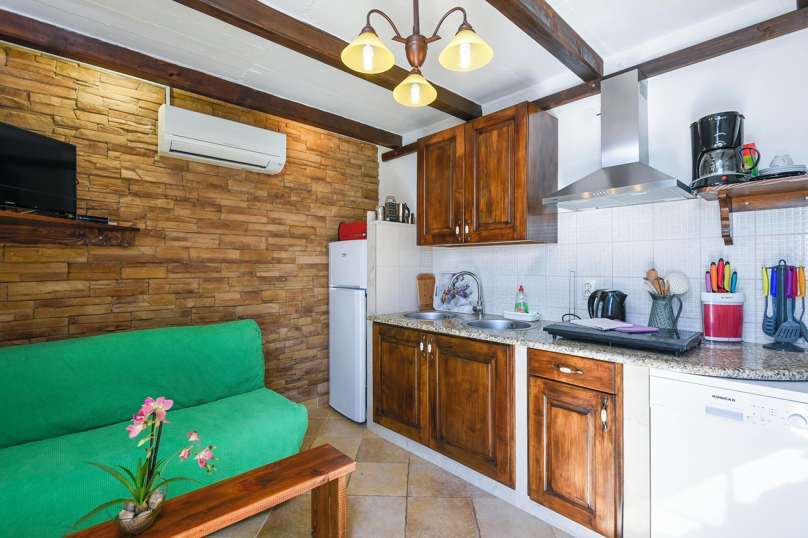 Una cocina compacta con gabinetes de madera, horno integrado y cafetera.