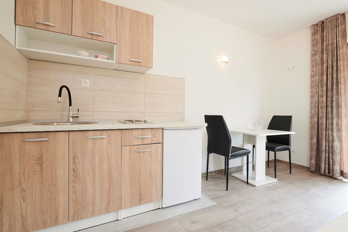 A modern kitchen with wooden cabinets, a white countertop, and a dining area with two black chairs.