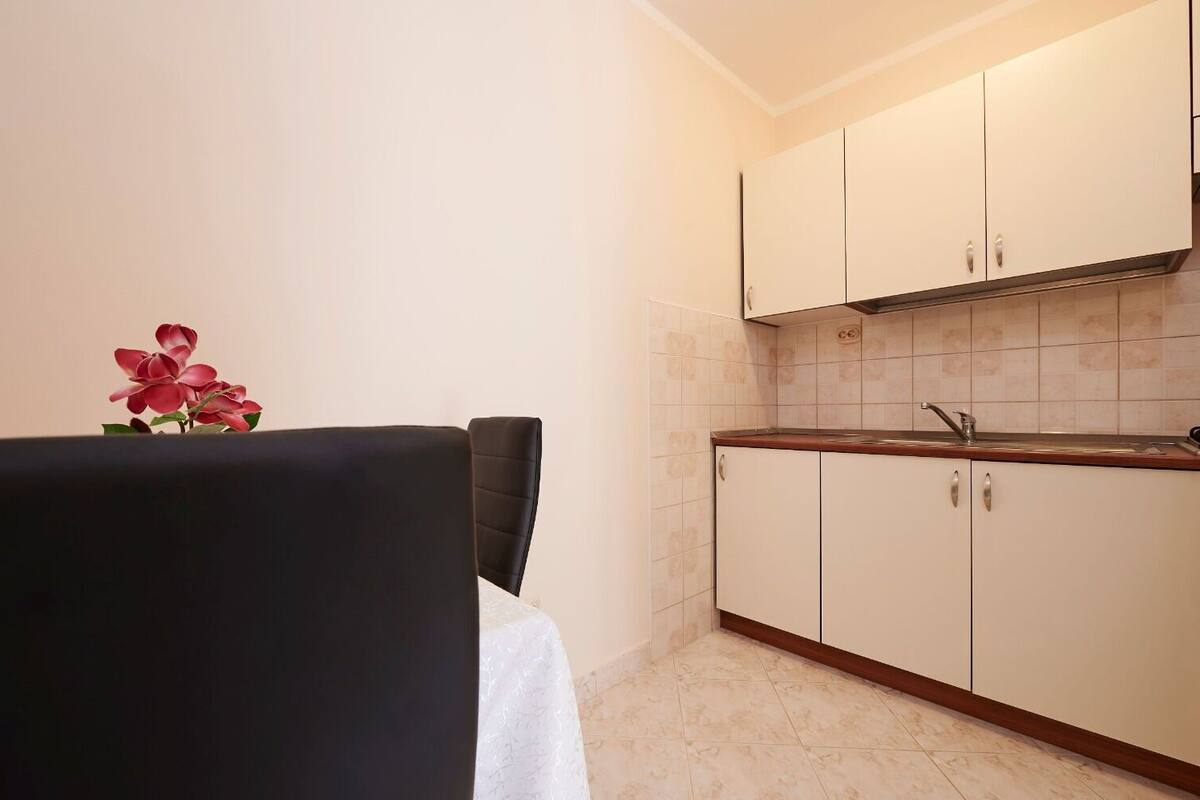 A compact kitchen with white cabinets, a wooden countertop, and a small sink.